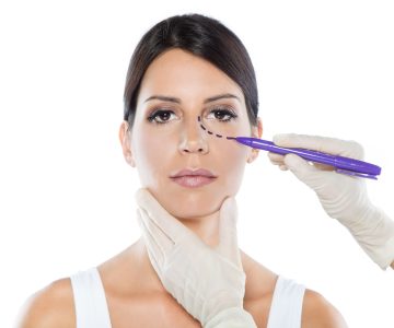 Portrait of plastic surgeon drawing dashed lines on her patient's face.